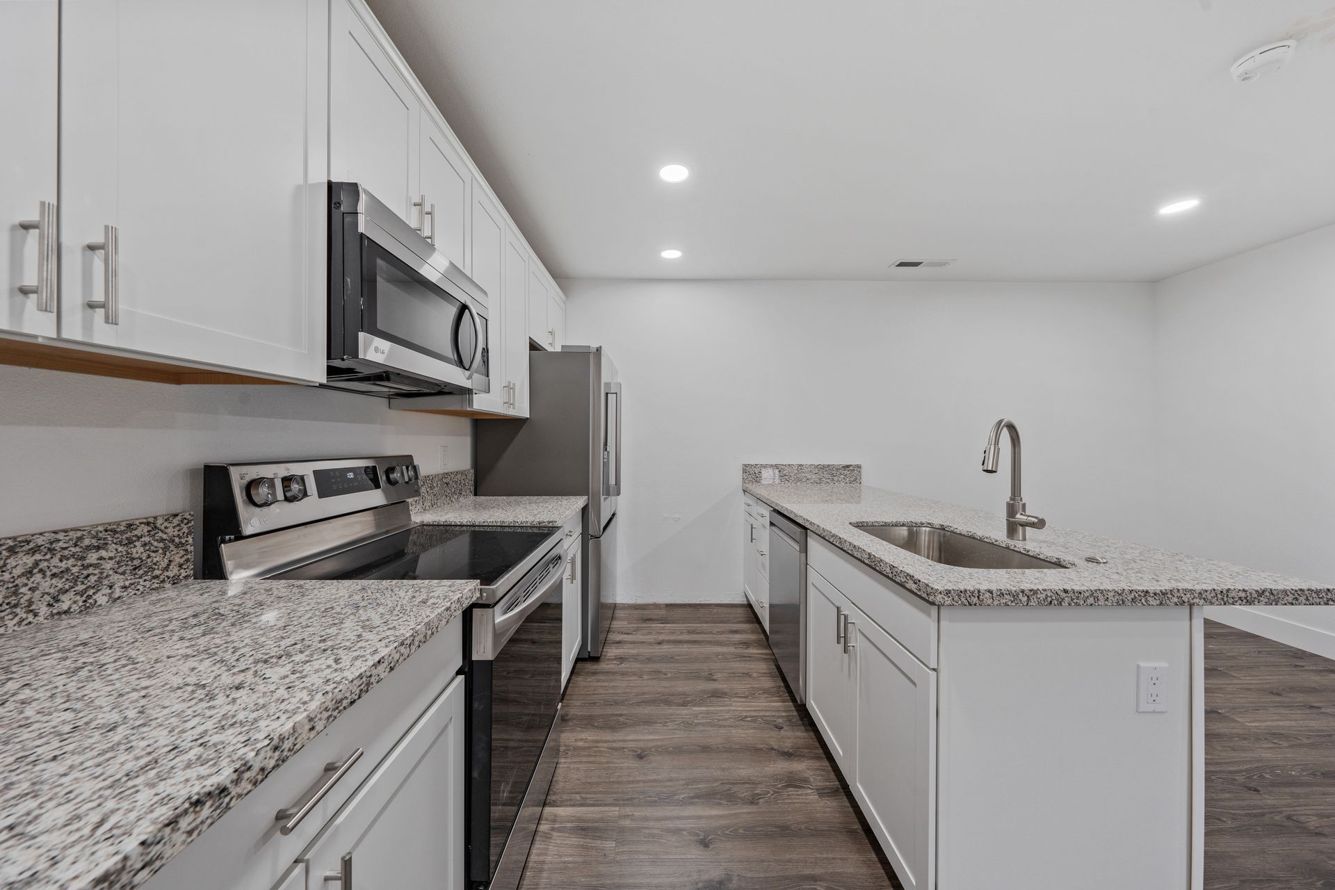 A kitchen with granite counter tops , stainless steel appliances , and white cabinets.