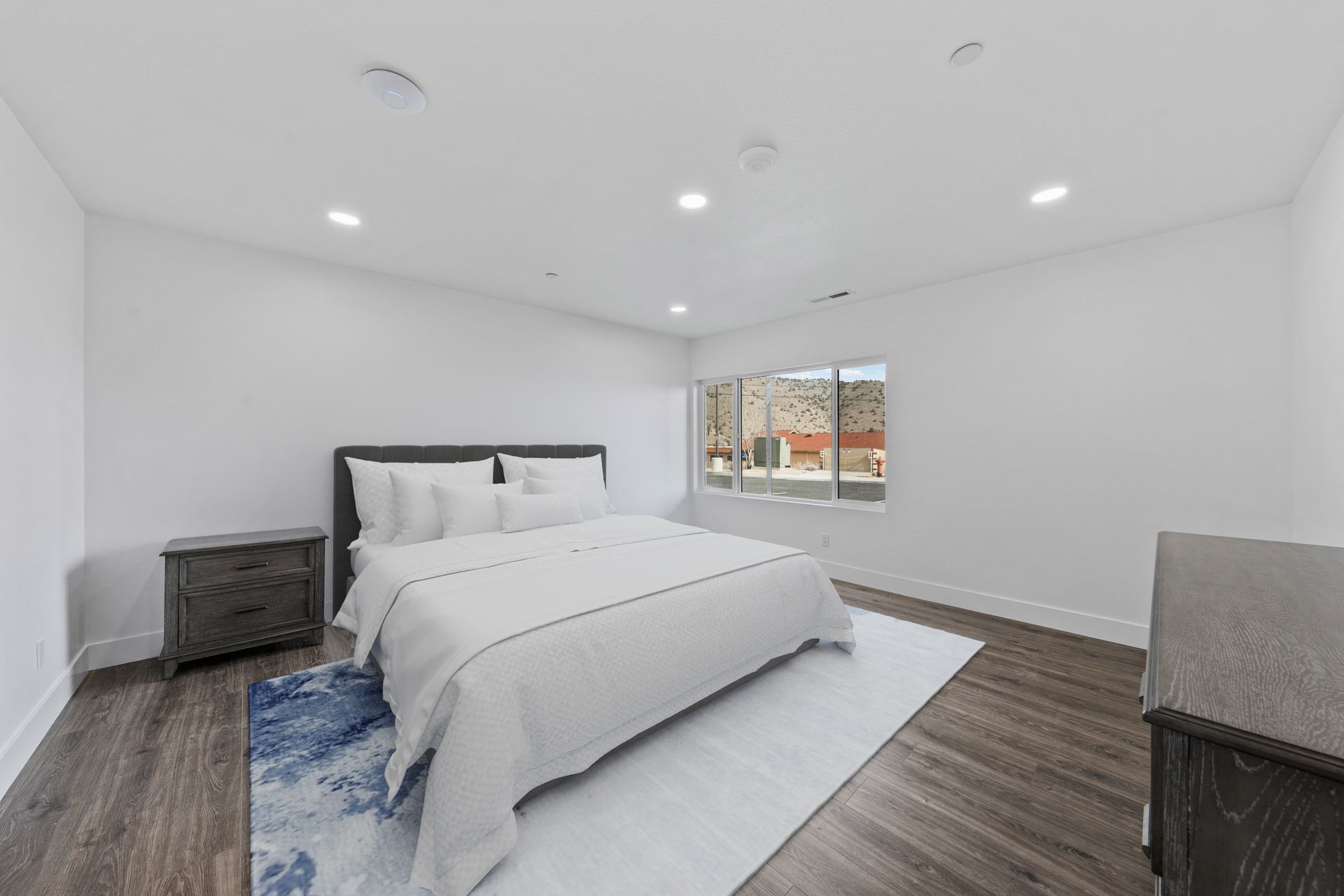 A bedroom with a king size bed , dresser , nightstand and rug.