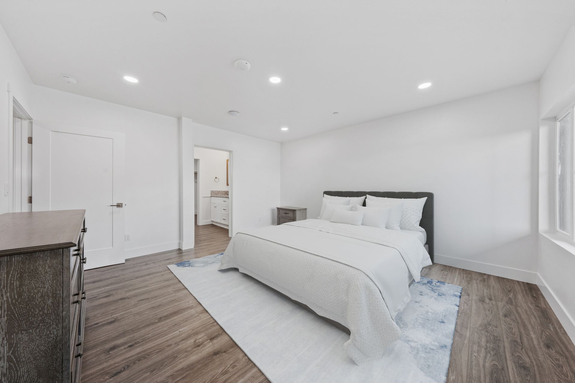 A bedroom with a large bed , dresser , and window.