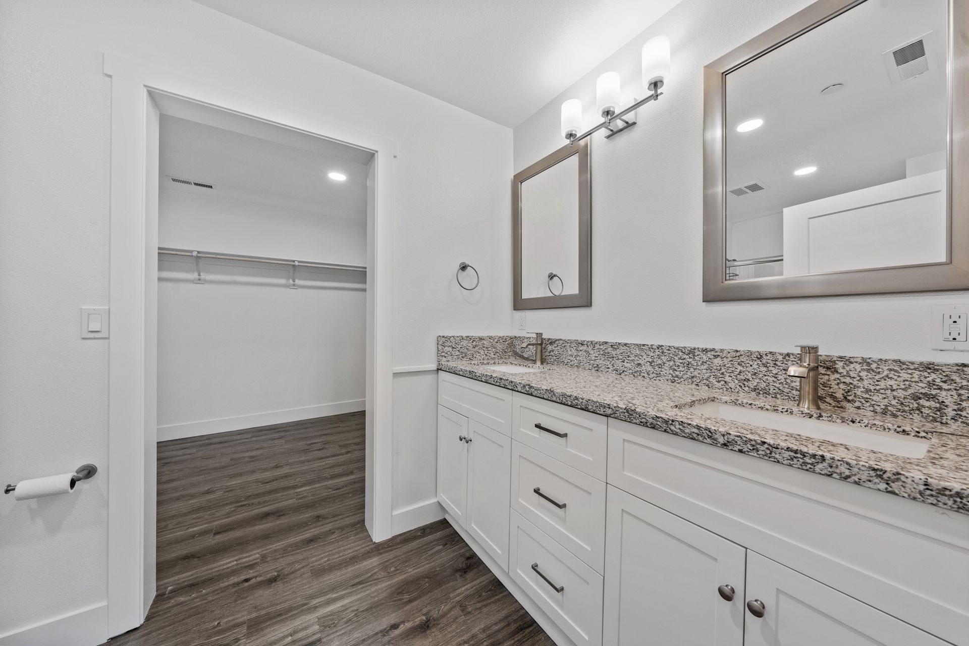 A bathroom with two sinks , a mirror and a walk in closet.