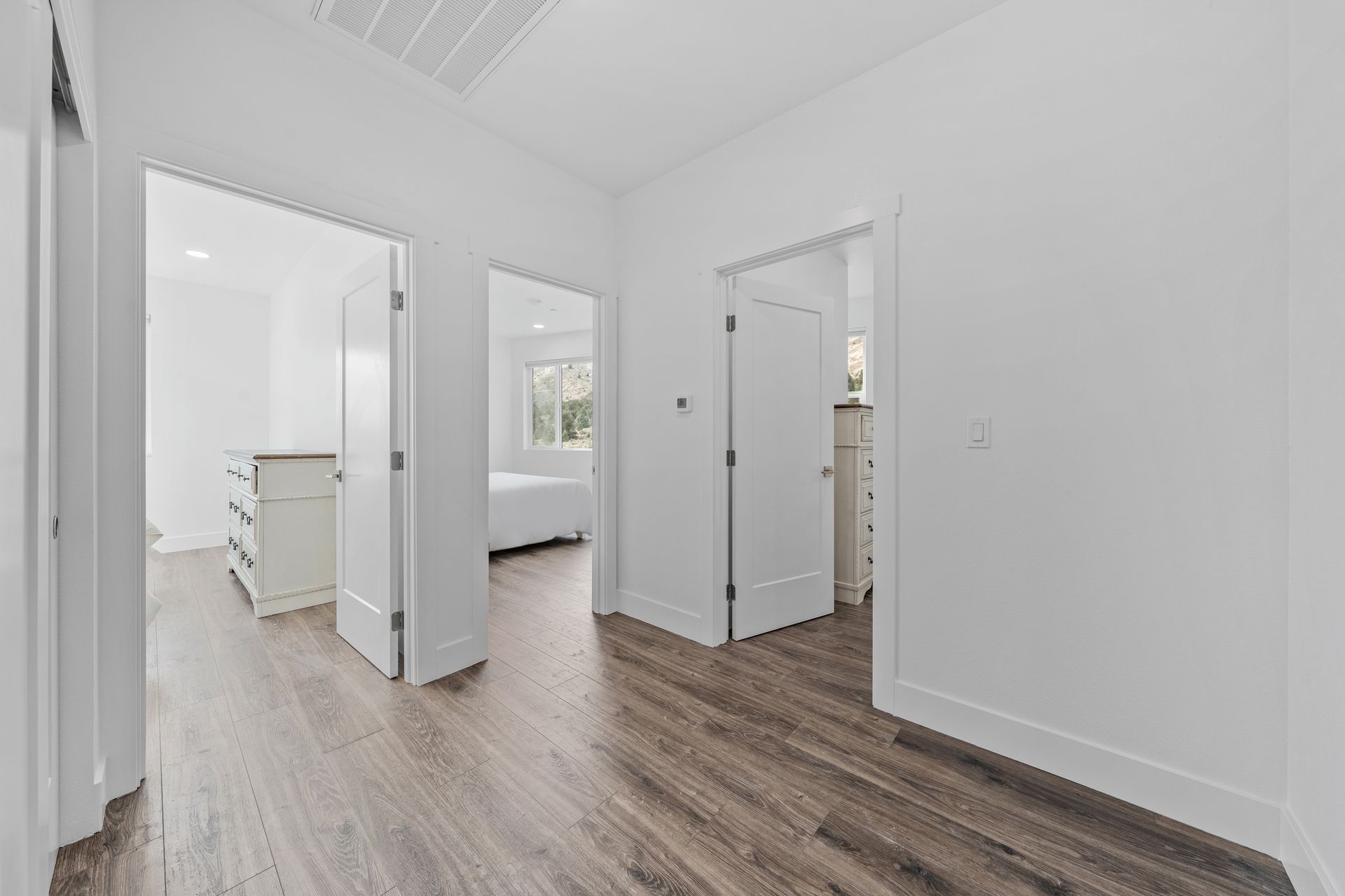 A hallway in a house with hardwood floors and white walls.