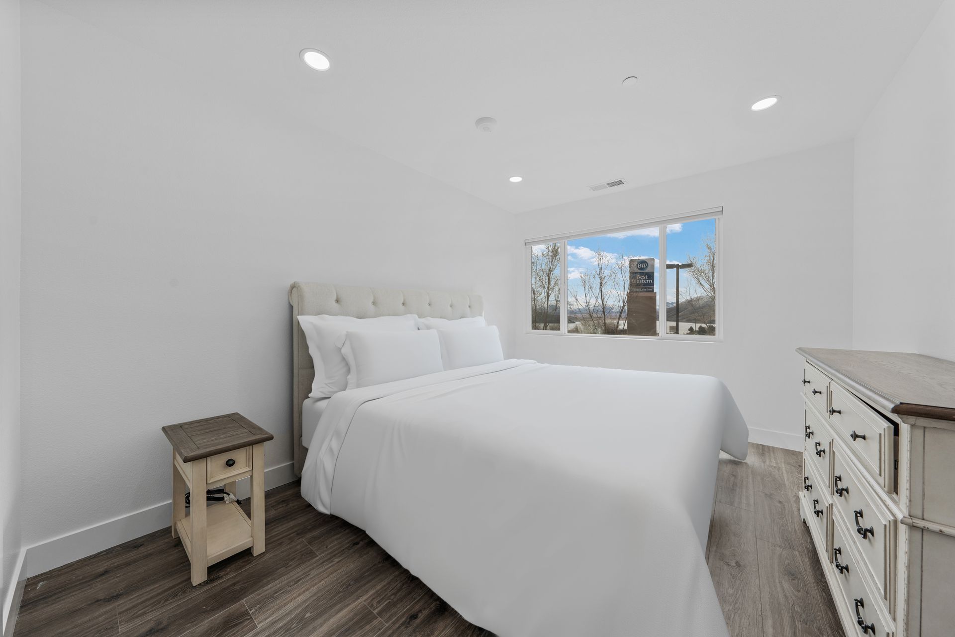 A bedroom with a bed , dresser , nightstand and window.