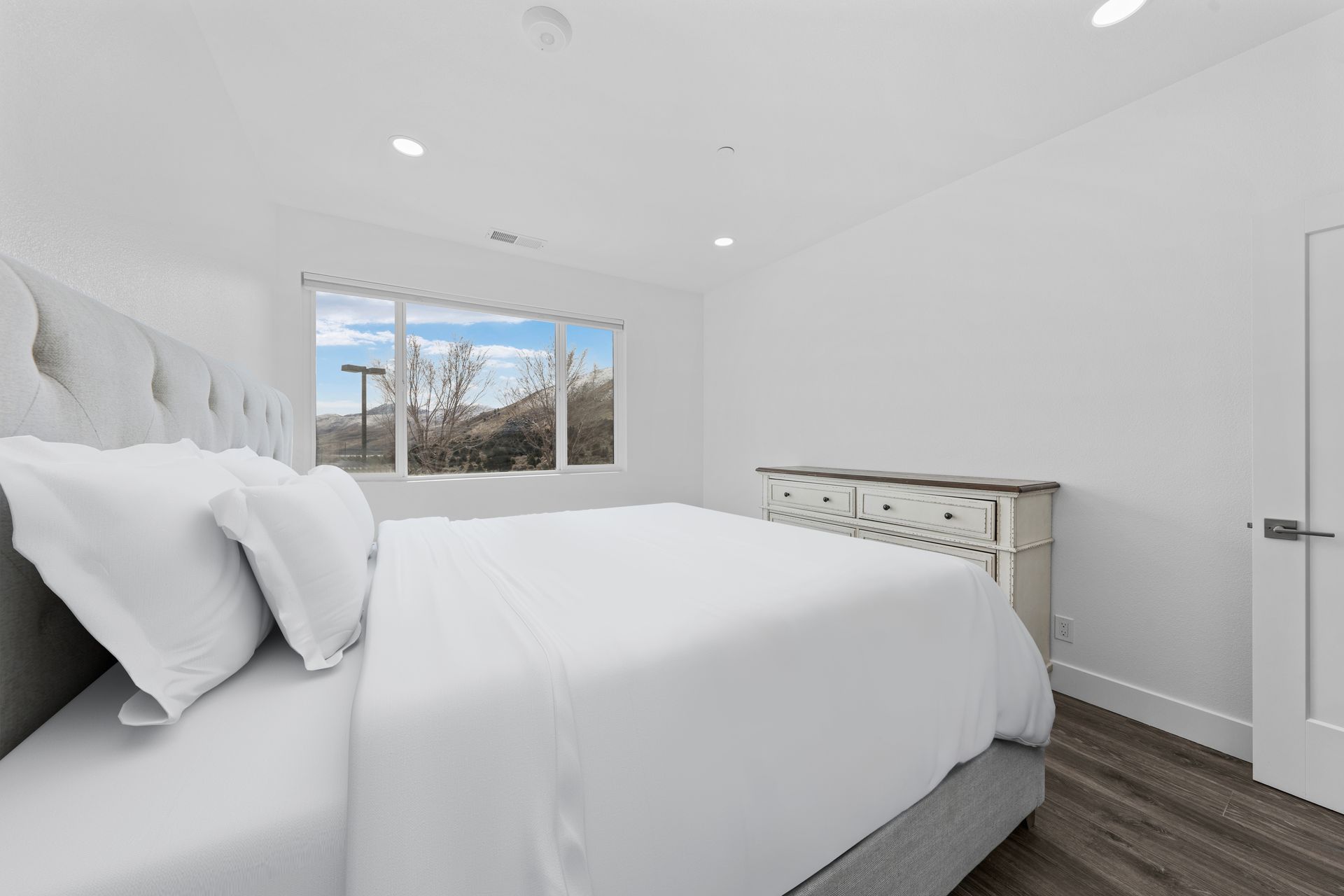 A bedroom with a large bed , dresser , and window.