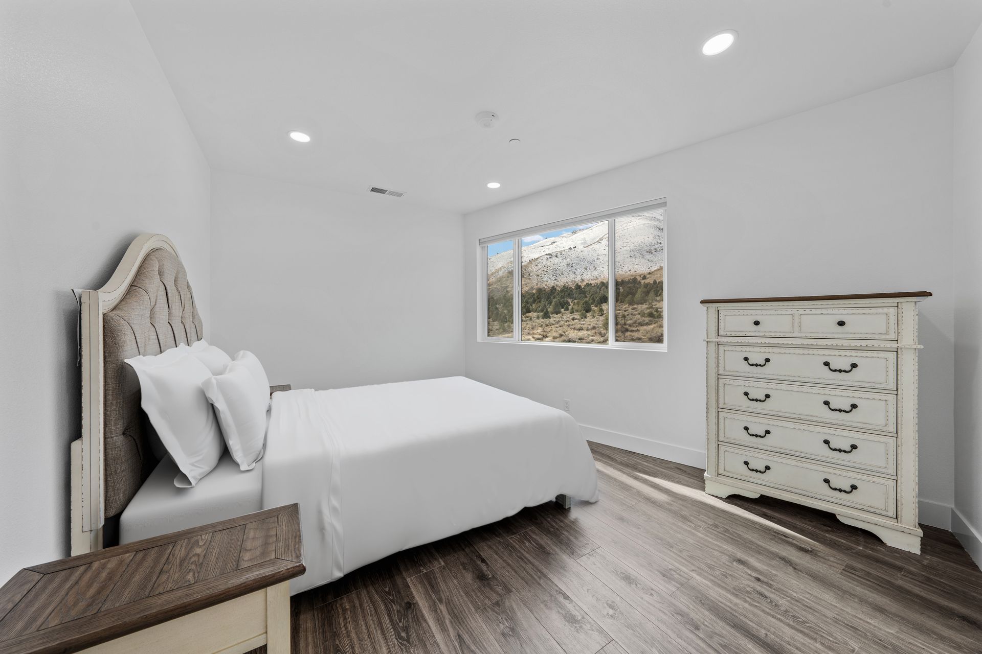 A bedroom with a bed , dresser , nightstand and two windows.