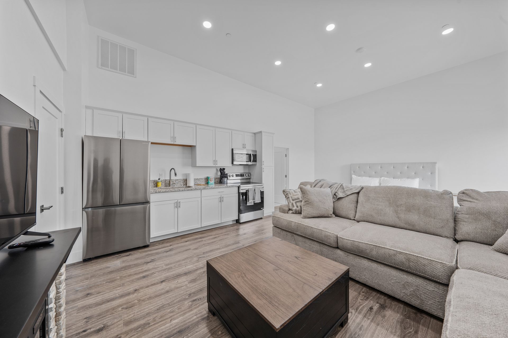 A living room with a couch , coffee table , television and kitchen.
