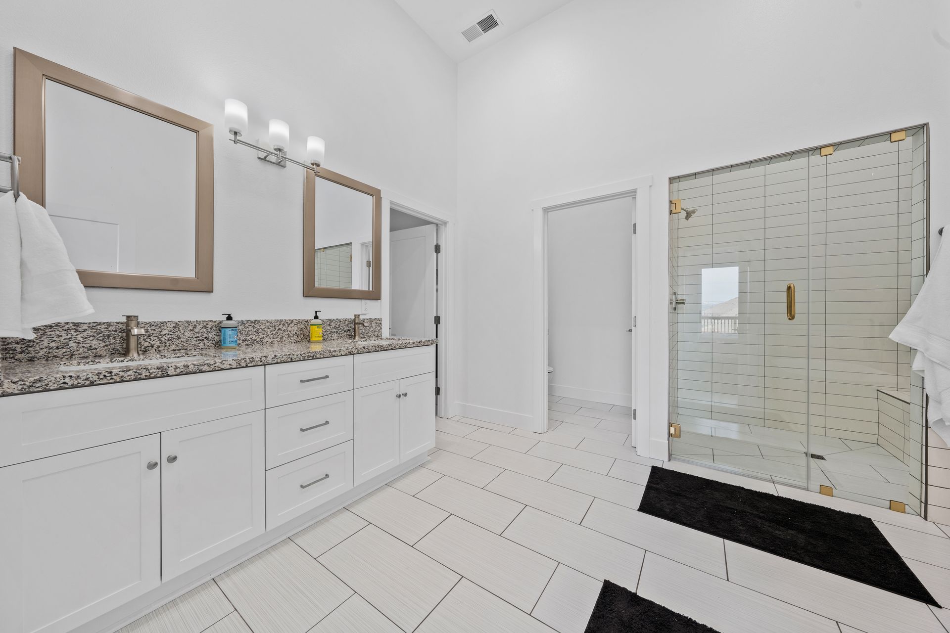 A bathroom with two sinks and a walk in shower.