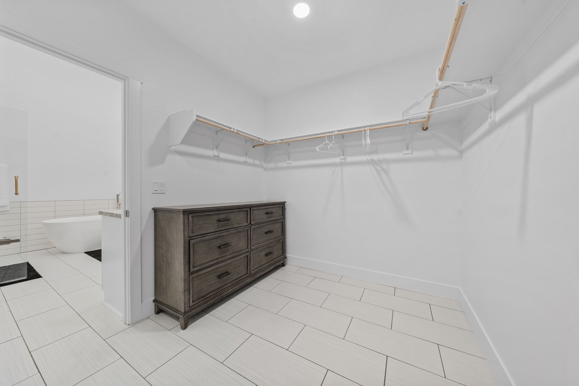 A walk in closet with a dresser and drawers in a bathroom.