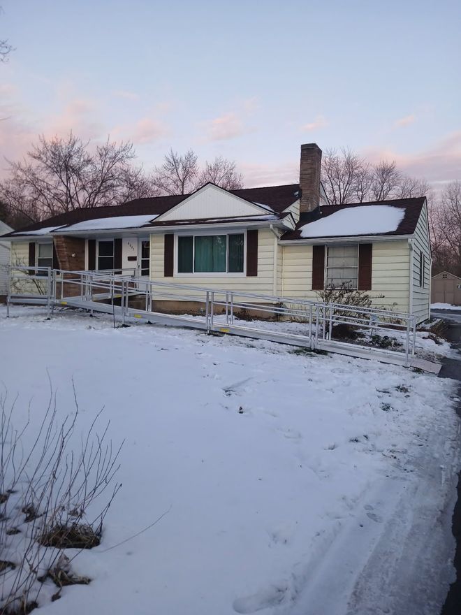An elderly woman is holding onto a railing in a bathroom.