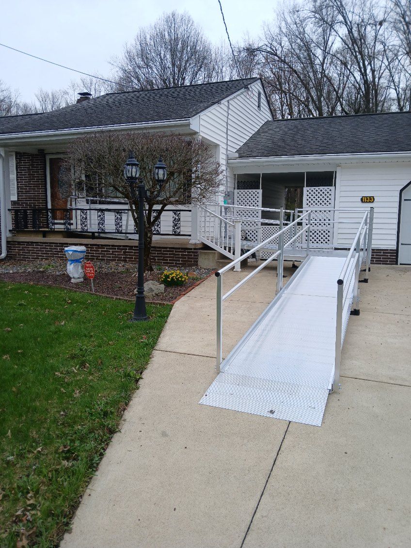 A white house with a wheelchair ramp leading to the entrance. A light post and small tree sit in the yard.
