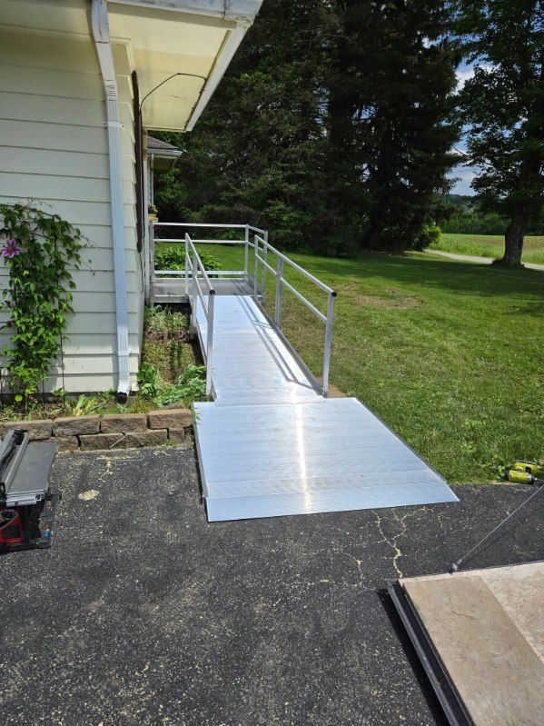 Silver ramp with handrails leads to a building entrance; it is on a grassy lawn.