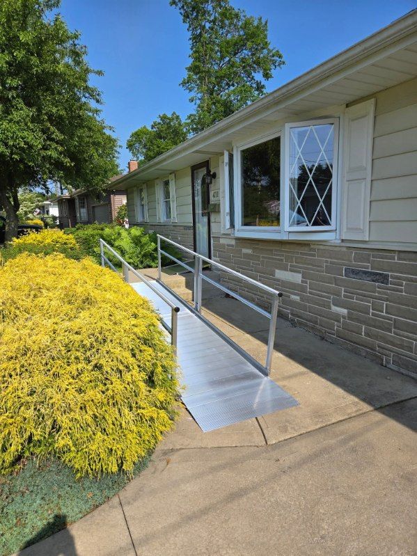 A house with a ramp leading to the entrance. Ramp has handrails, a window, and beige siding.
