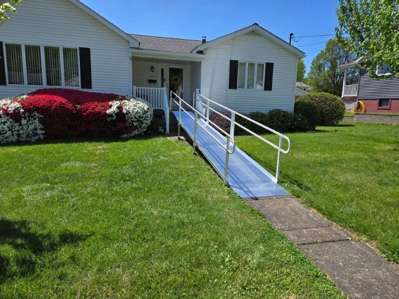 White house with a blue ramp for accessibility. Green lawn, sunny day.