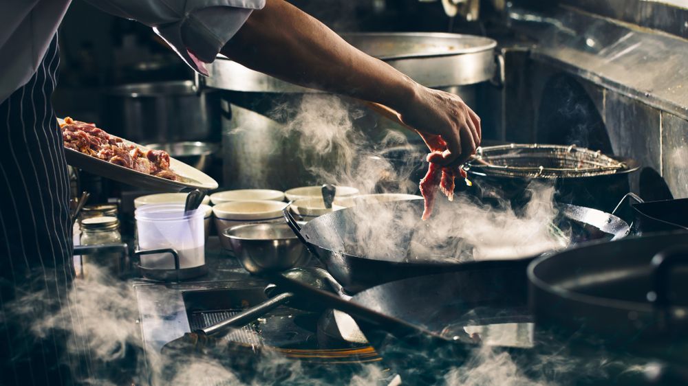Chef Cooking in a Steamy Kitchen, Adding Ingredients to a Wok — Chefs2Go in Ayr, QLD