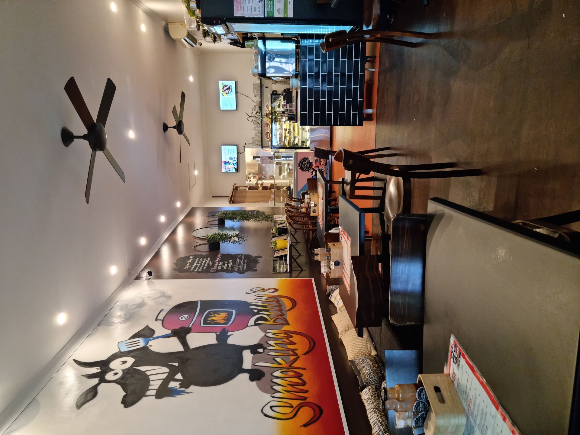Cafe interior with tables, ceiling fans, and a mural— Chefs2Go in Whitsunday, QLD