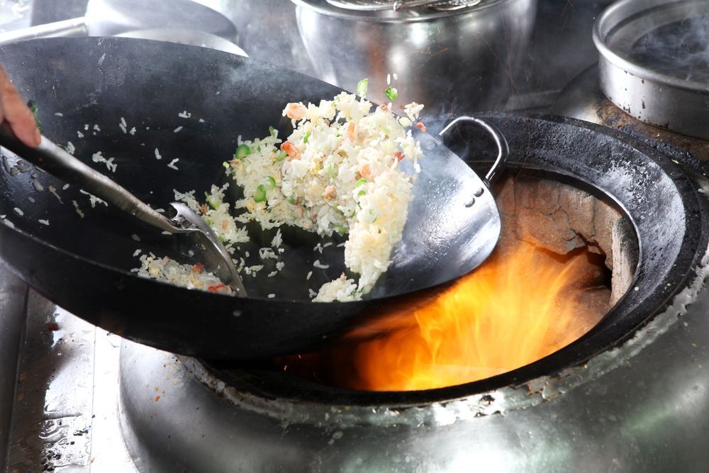 Wok Frying Rice Over Open Flame. a Hand Stirs the Ingredients in a Large, Black Wok — Chefs2Go in Bowen, QLD
