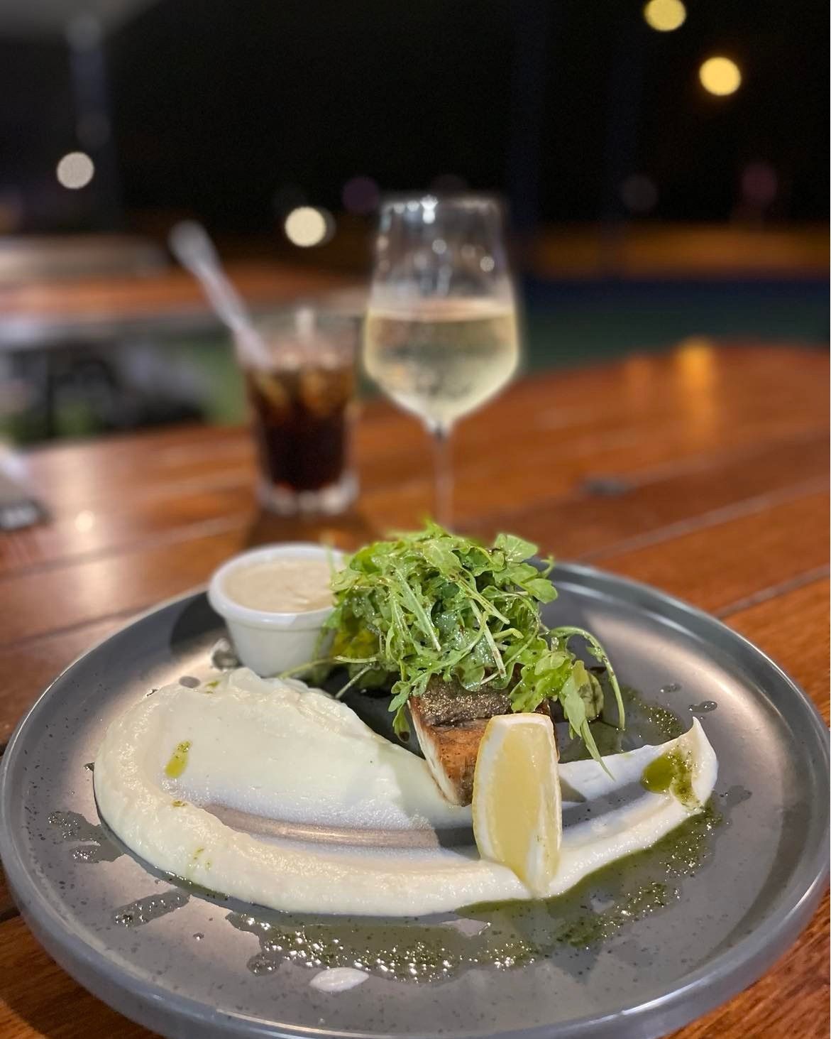 Plate of Fish With Mashed Potatoes and Greens, a Glass of Wine and Cola on a Wooden Table — Chefs2Go in Darwin, NT