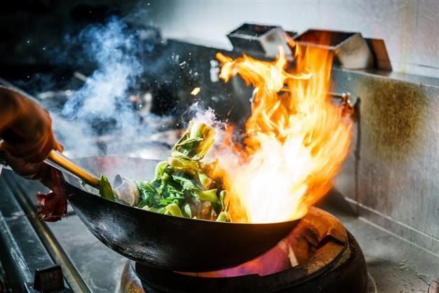A Wok With Food on Fire Inside, Flames Rising High in a Commercial Kitchen Setting — Chefs2Go in Sunshine Coast, QLD