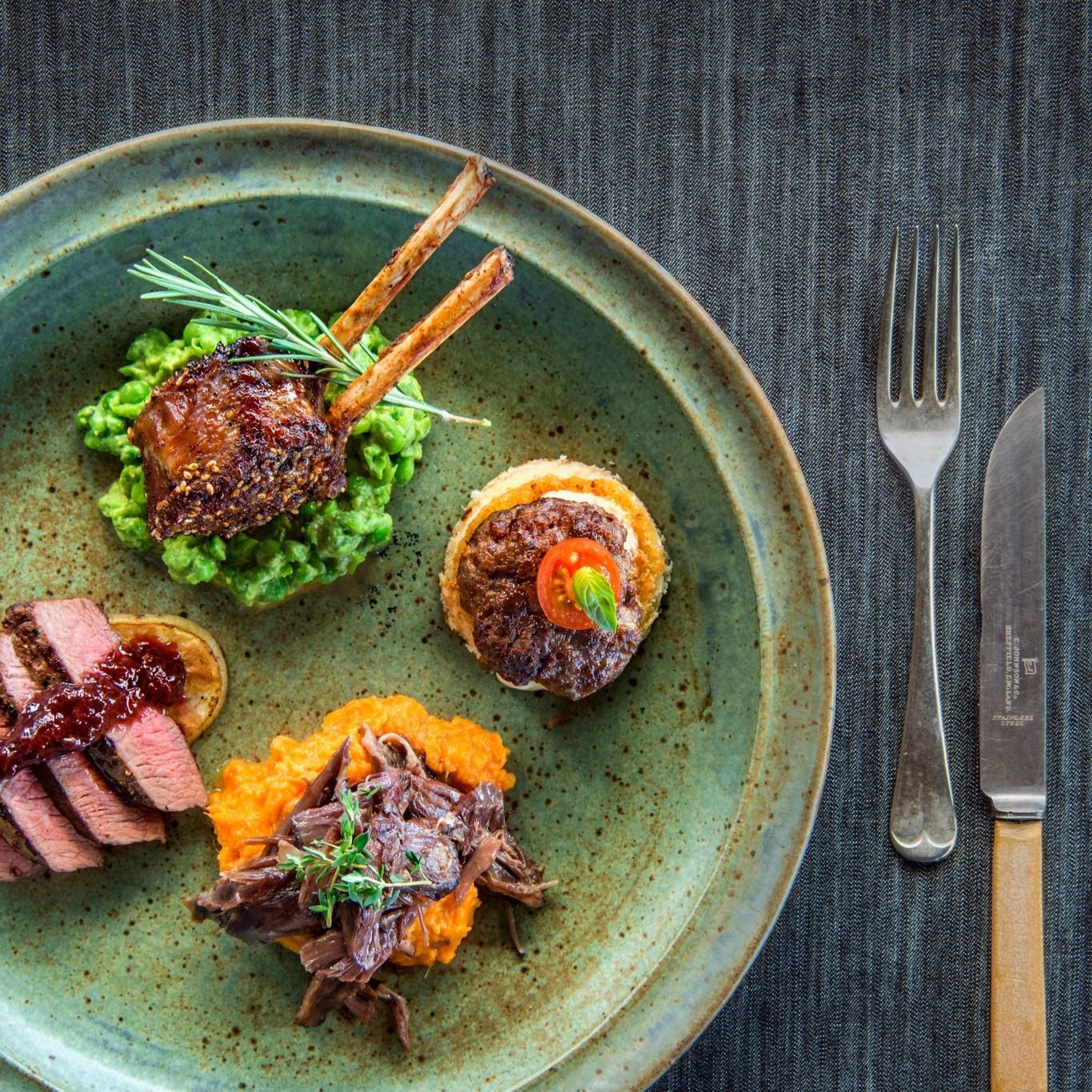 Plate of Gourmet Food With Lamb Chop, Steak, and Sides, With Silverware — Chefs2Go in Gladstone, QLD