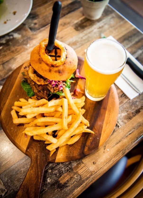 Burger With Onion Rings and Fries on Wooden Board, With a Pint of Beer — Chefs2Go in Gladstone, QLD