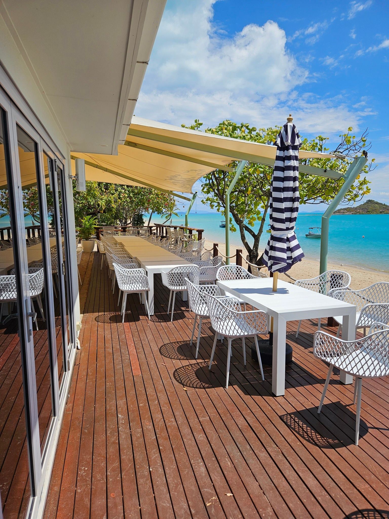 Outdoor Dining Area With Tables, Chairs, and Umbrella on a Wooden Deck — Chefs2Go in Woodwark, QLD