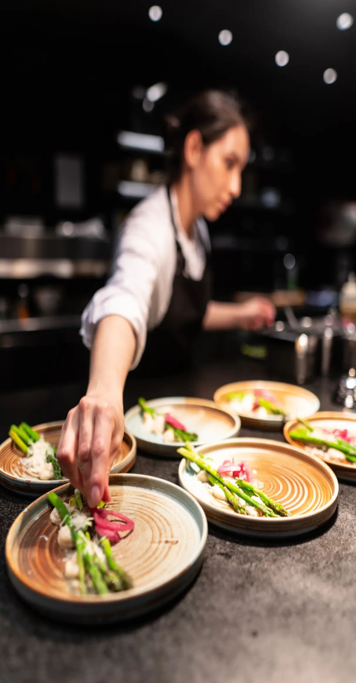 Chef Plates Asparagus and Radishes on Several Dishes in a Kitchen Setting — Chefs2Go in Woodwark, QLD