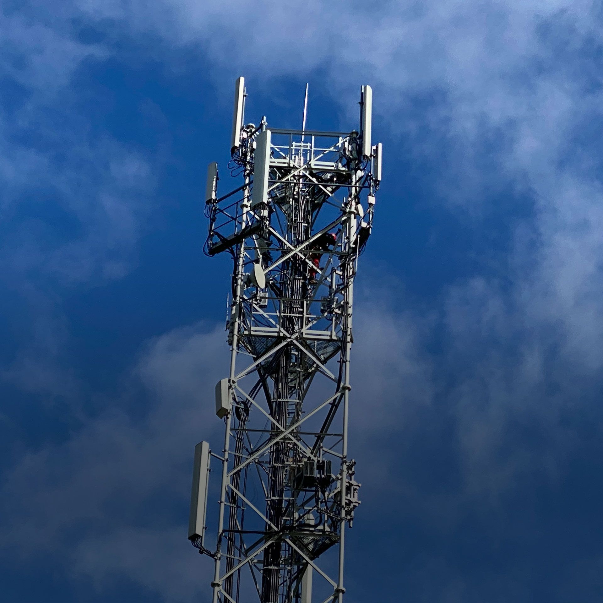 Une haute tour avec des antennes au sommet contre un ciel bleu nuageux.