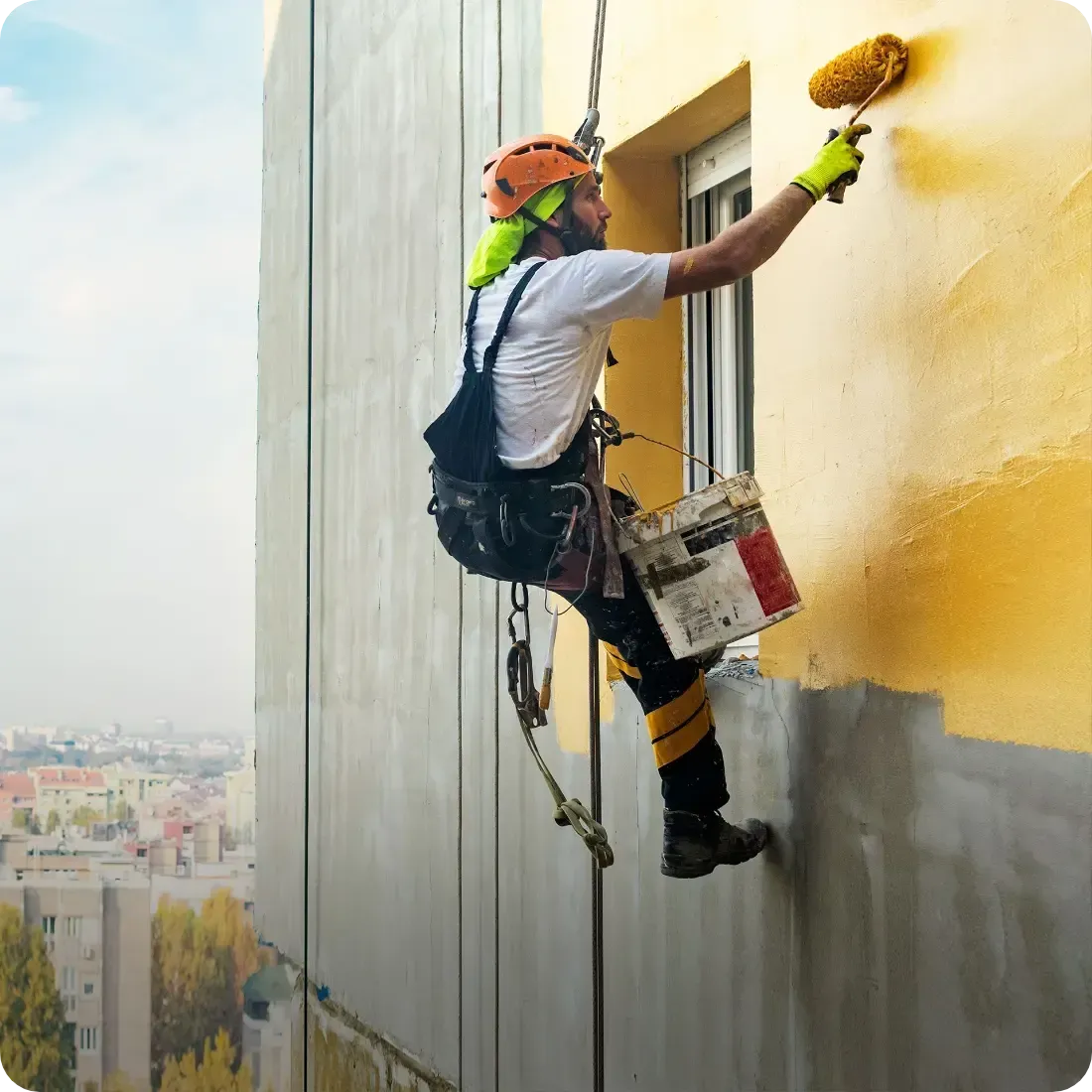 Un homme peint le côté d'un bâtiment avec un rouleau.
