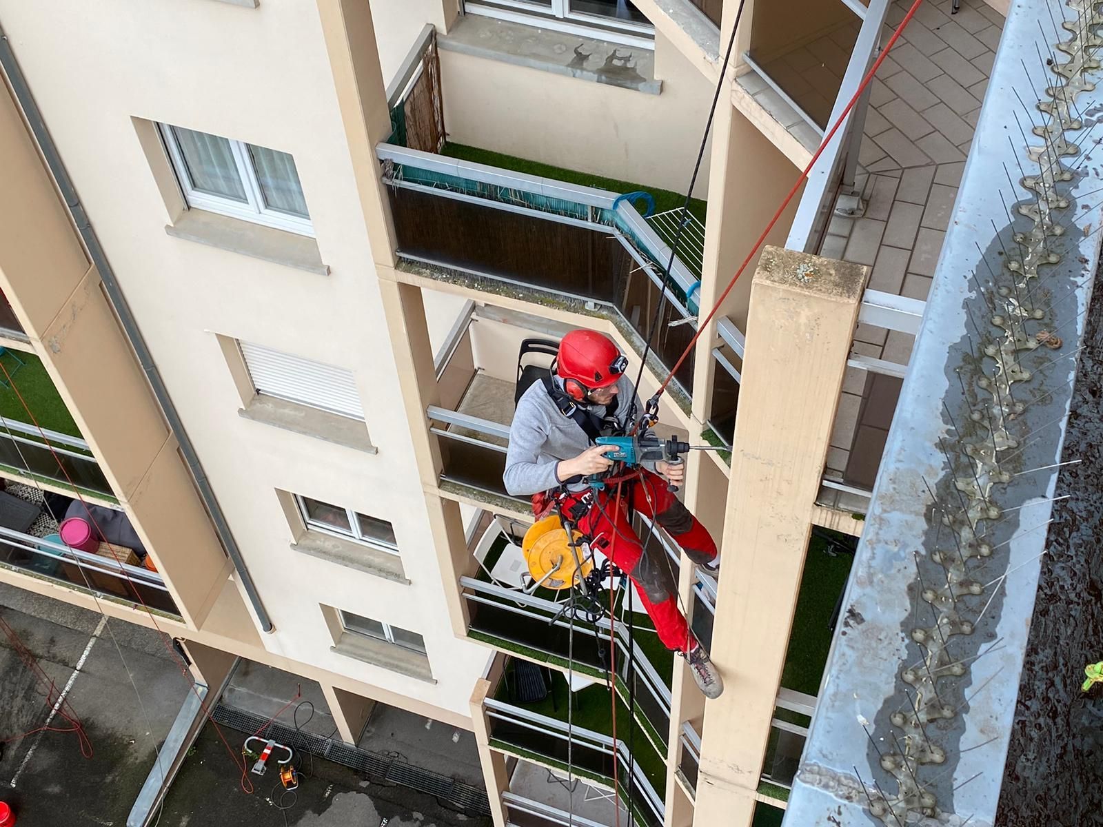 Un homme grimpe sur le côté d'un grand bâtiment.