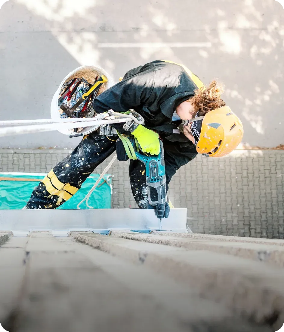 Un homme portant un casque utilise une perceuse sur un mur.