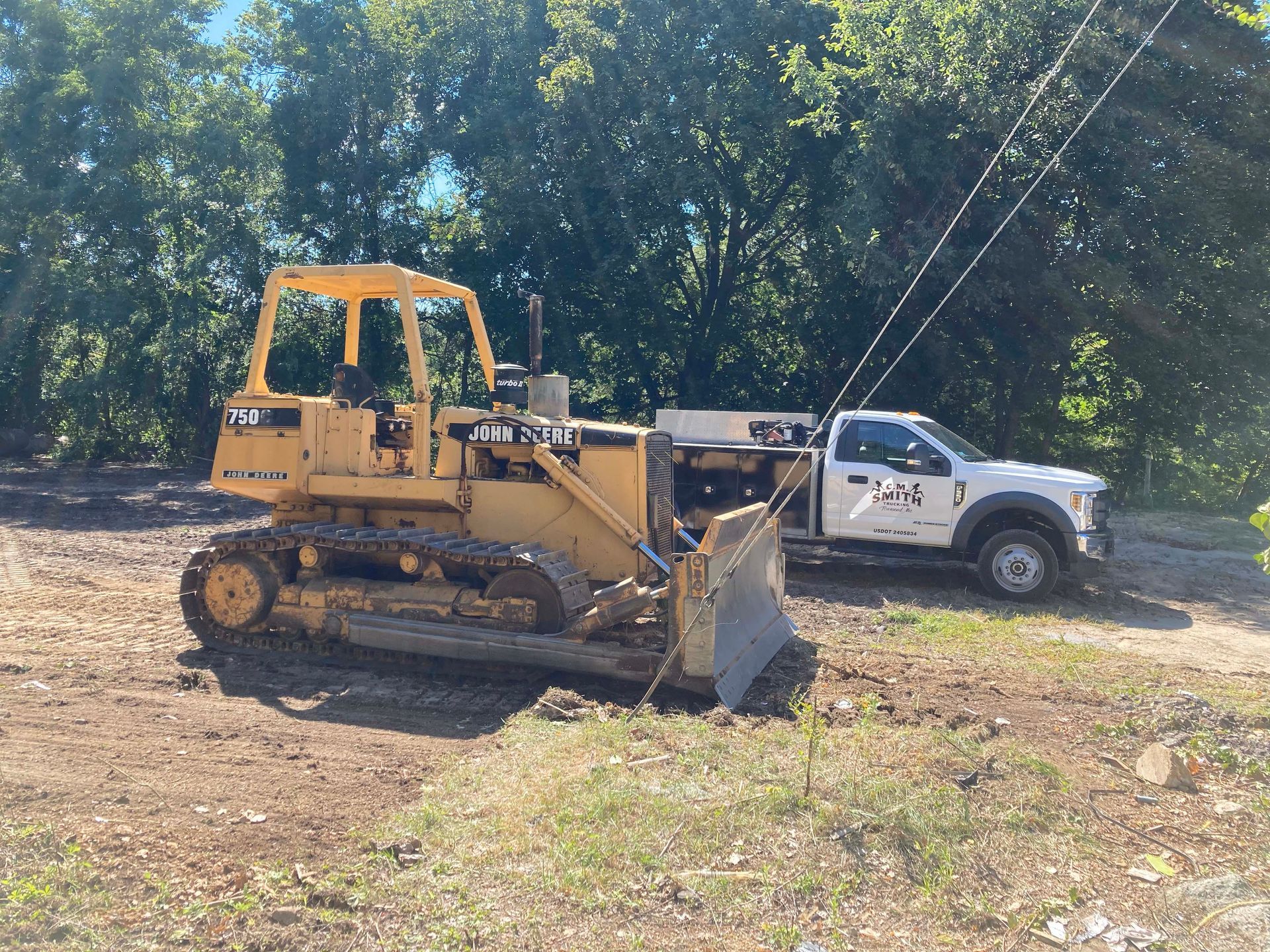 A bulldozer is parked next to a white truck.