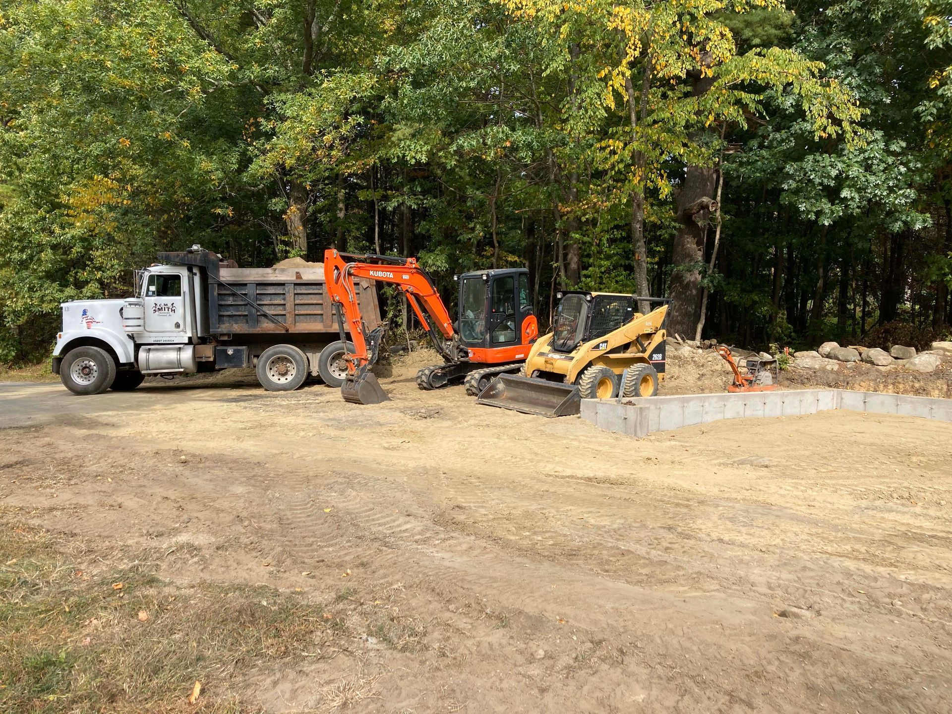 A dump truck and an excavator are parked in a dirt field.
