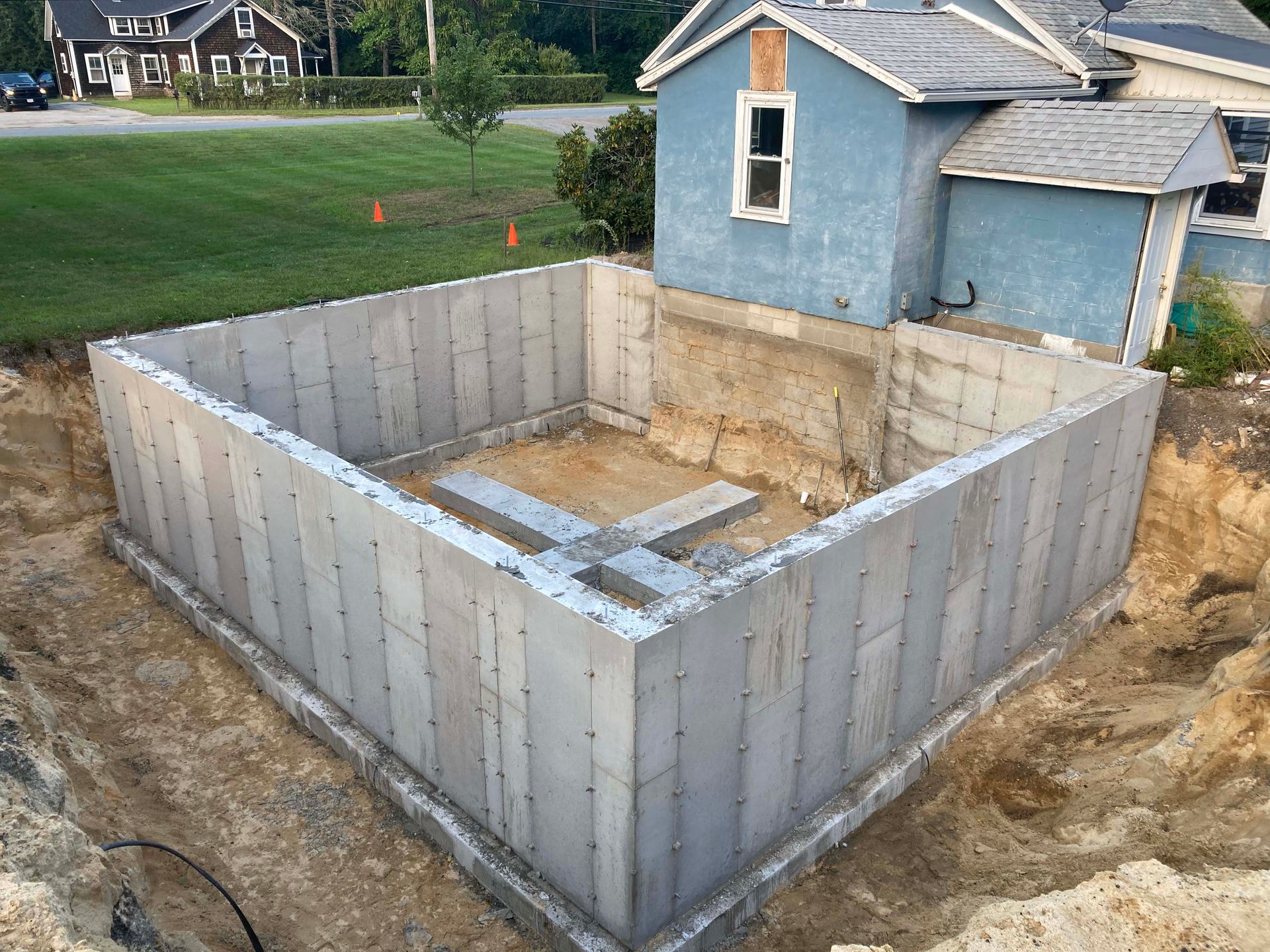 A large concrete basement is being built in front of a blue house.