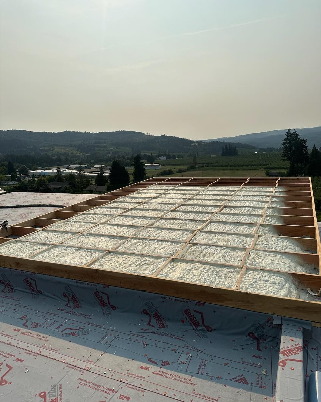 The roof of a building is being built and there is a view of the mountains in the background.
