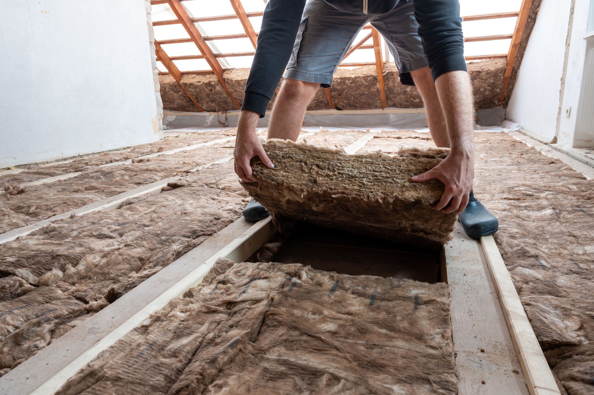 A man is rolling a piece of insulation on the floor.