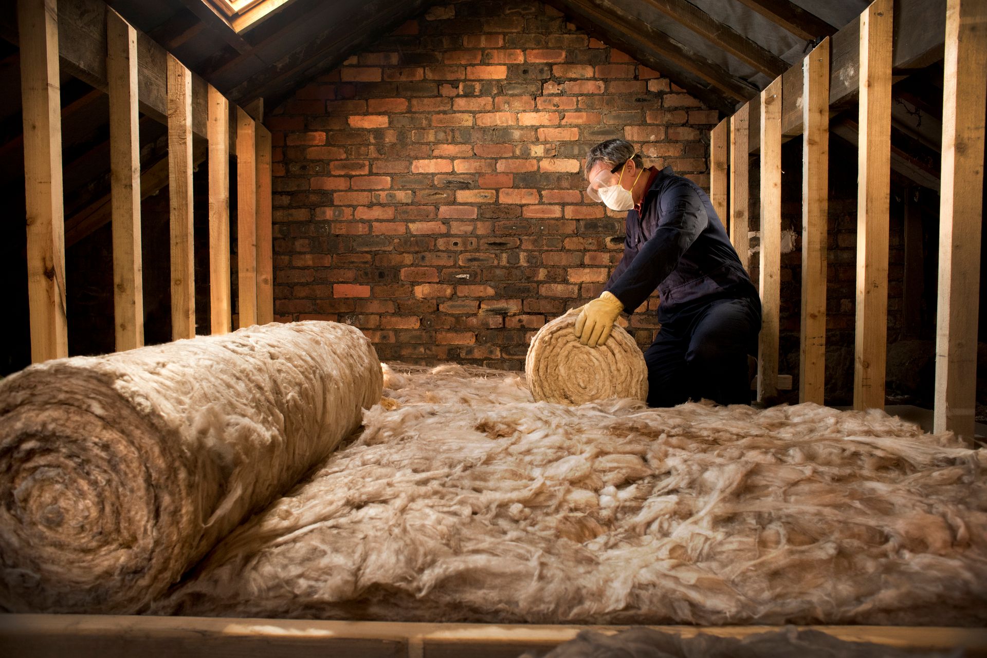 A man is installing insulation in an attic.