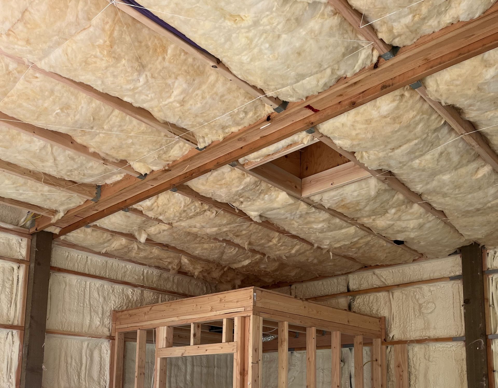 A man is measuring a piece of insulation with a tape measure.