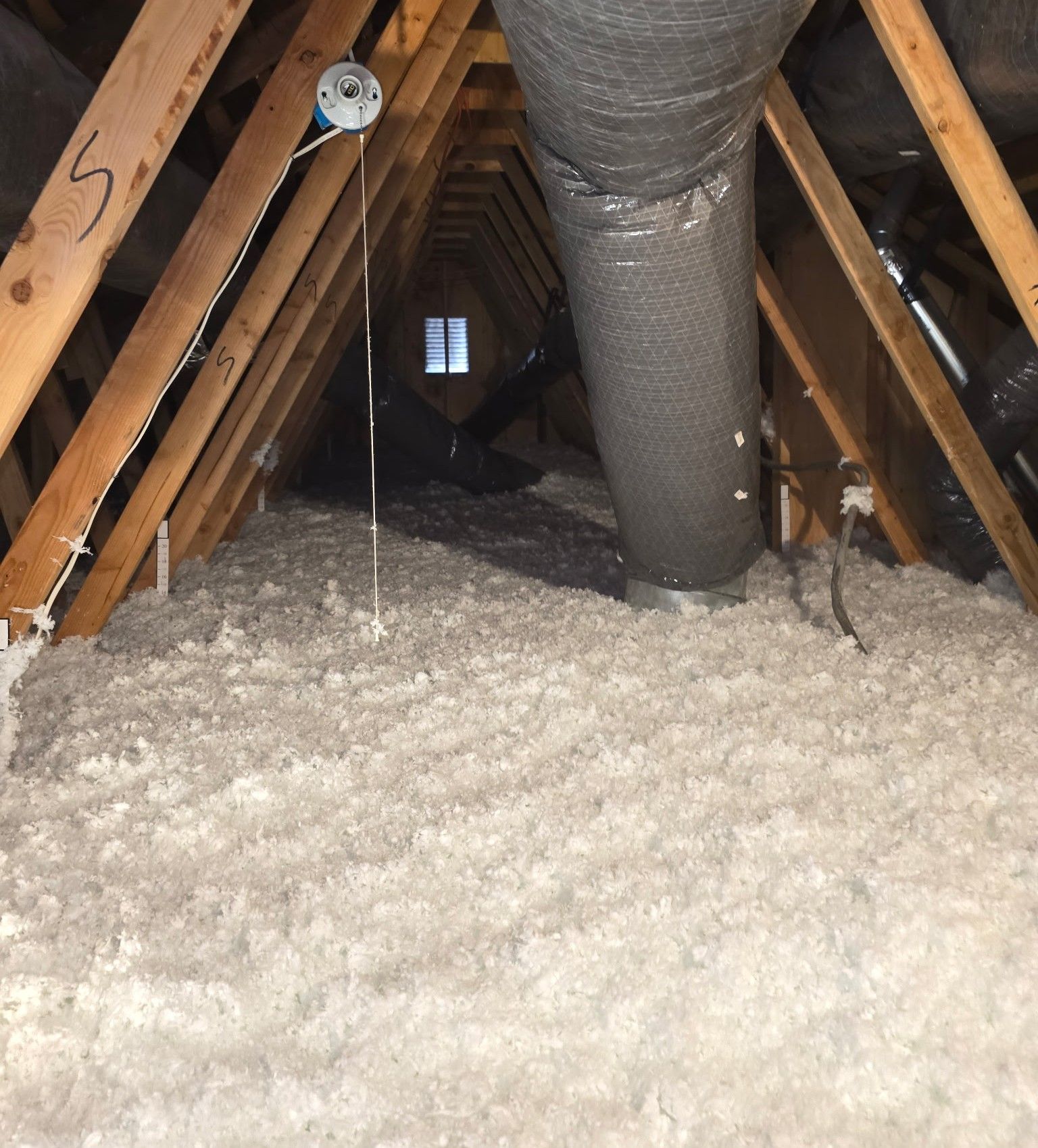 A person is blowing insulation into the attic of a house.