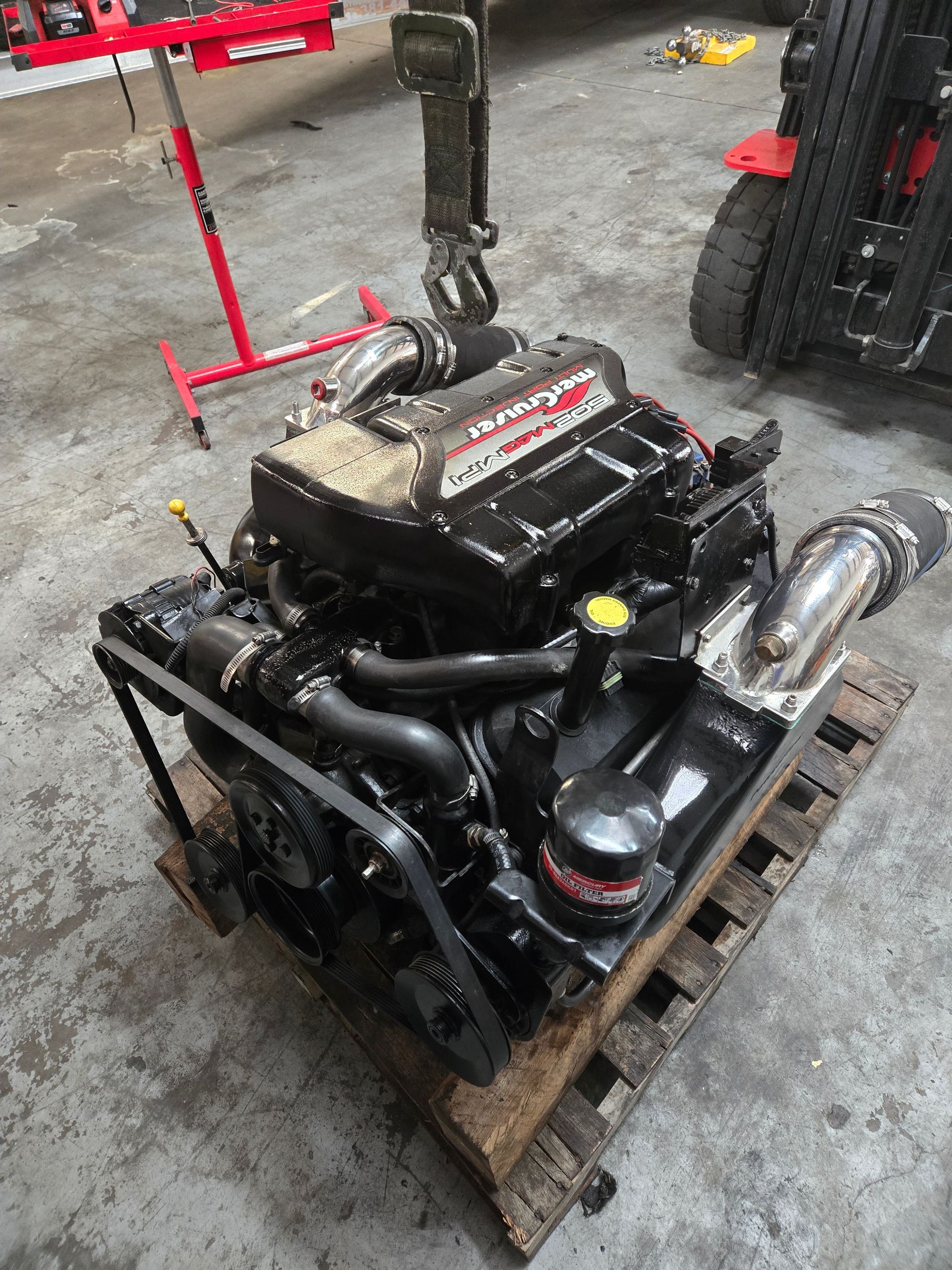 A black engine is sitting on a wooden pallet in a garage.