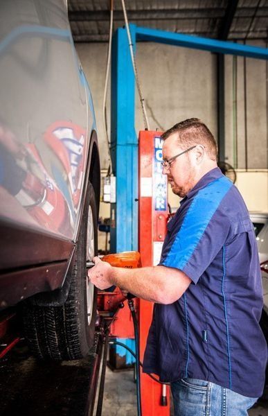 Mechanic Working on A Car Wheel with A Wrench โ DK Mechanical Repairs in Warners Bay, NSW