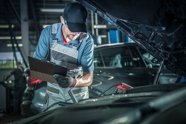 Mechanic in Overalls Inspecting a Car Engine with A Clipboard โ DK Mechanical Repairs in Warners Bay, NSW