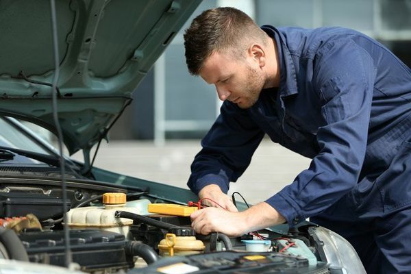 Mechanic in Blue Jumpsuit Working on Car Engine Using a Multimeter โ DK Mechanical Repairs in Warners Bay, NSW