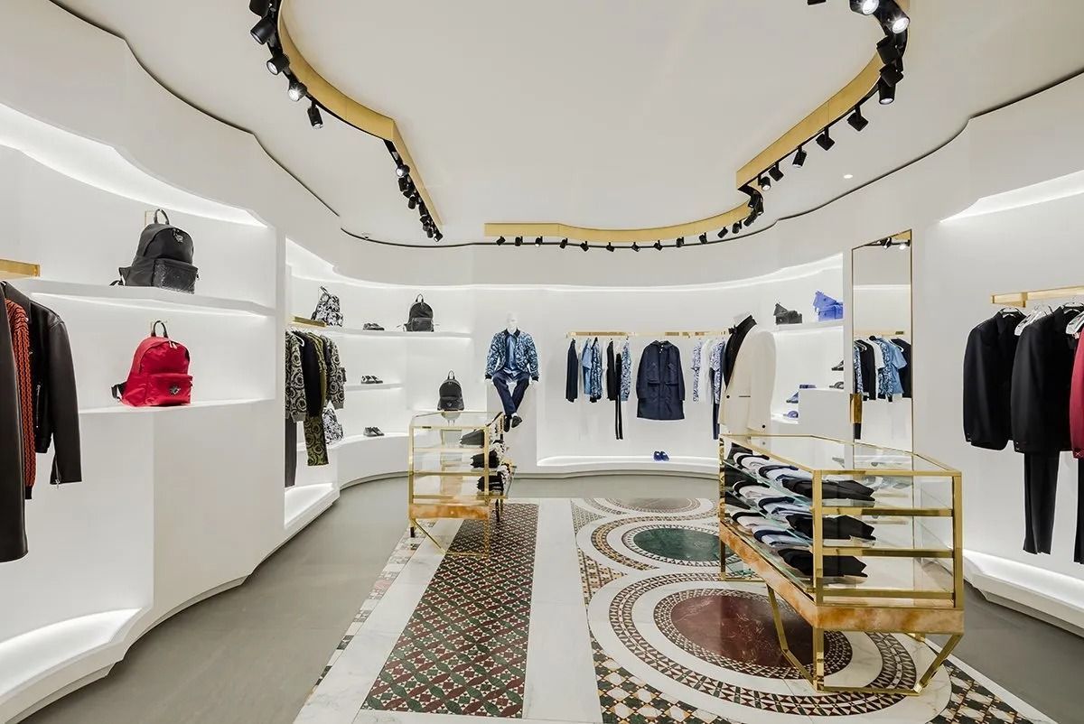 Interior de una boutique de ropa moderna con paredes blancas, estantes de exhibición y prendas colgadas.