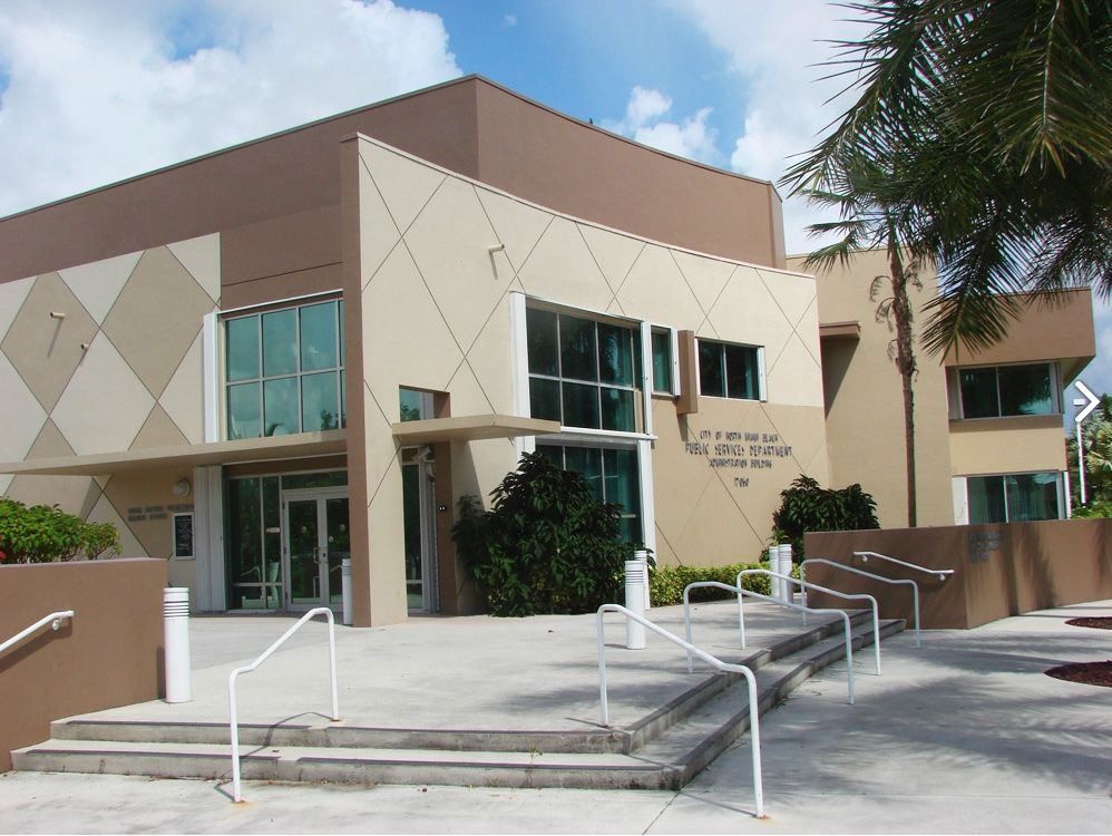 Modern building with tan and brown facade, glass windows, and a ramp for accessibility.
