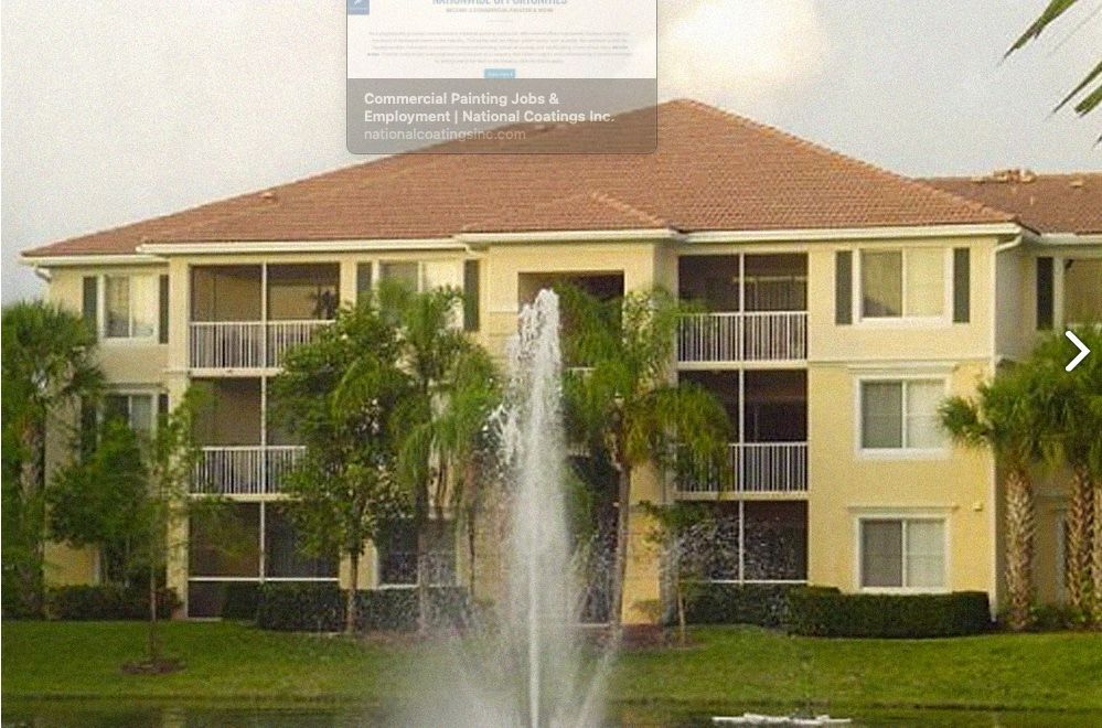 Apartment building with yellow exterior, red tile roof, and fountain in front of a lake.