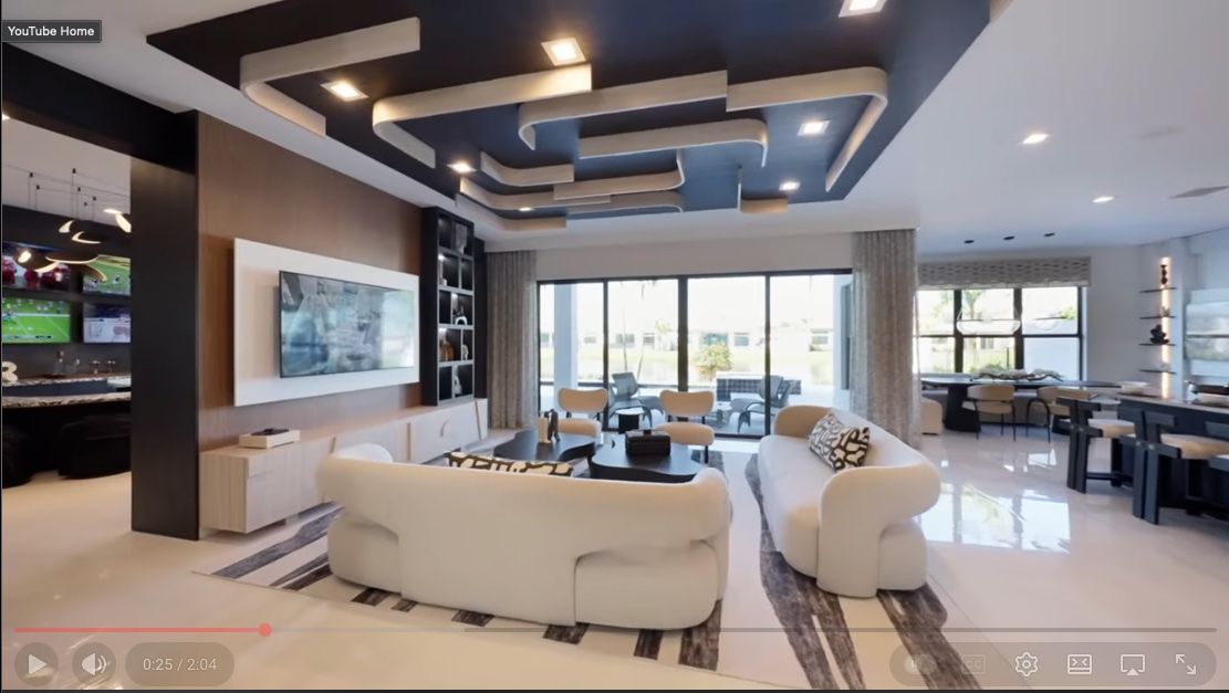 Modern living room with white sofas, large windows, and a decorative ceiling.