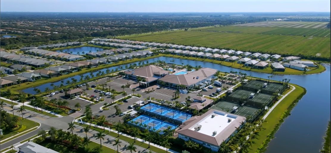Aerial view of a residential community with waterways, tennis courts, and a large clubhouse.