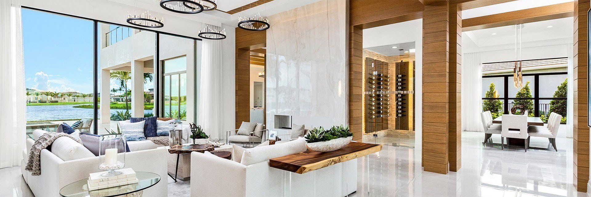 Luxurious modern living room with water view, white furniture, and a wine cellar.
