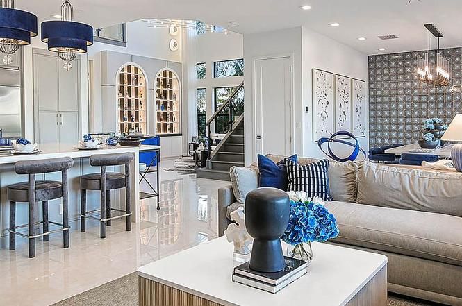 Open-plan living space with kitchen, living room, and staircase. Blue and white decor; neutral tones, modern.