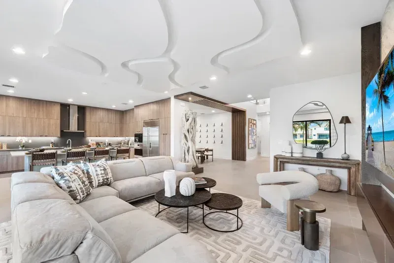 Spacious living room with a large sectional sofa, coffee tables, and a modern, decorative ceiling.