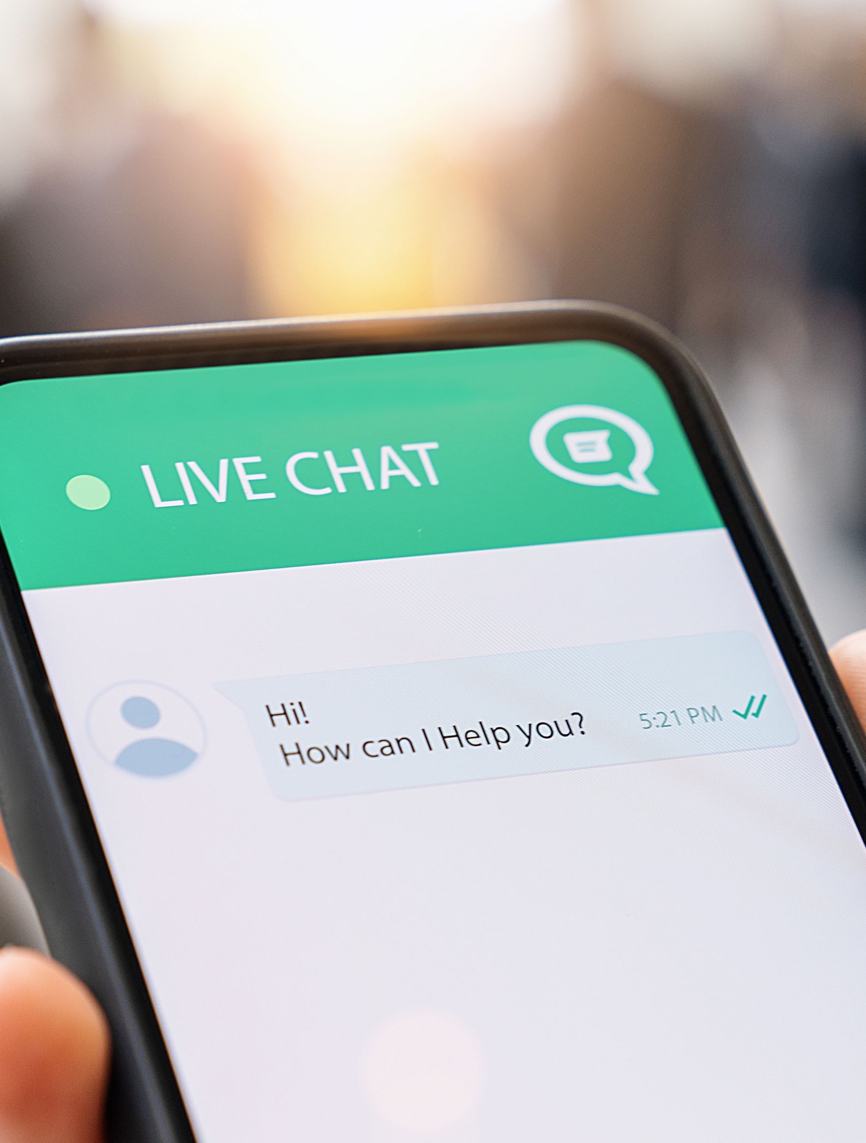A person is holding a cell phone with a live chat app on it.